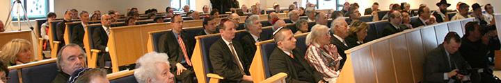 Besucher/innen in den vollbesetzen Holzbänken der Synagoge